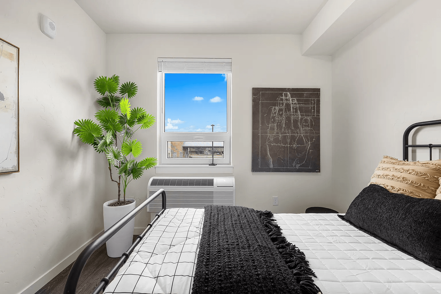 A bedroom with a large bed and a potted plant.